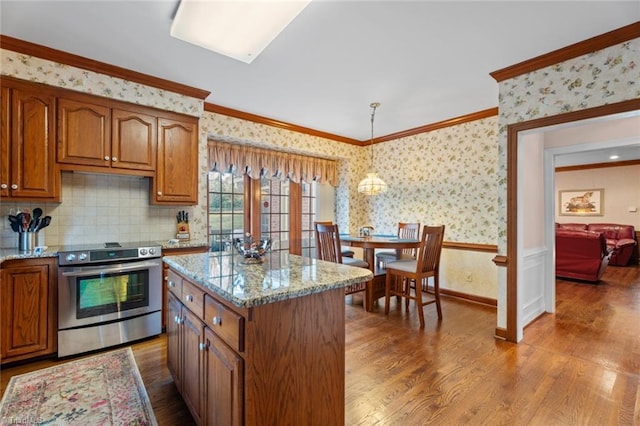 kitchen with wallpapered walls, brown cabinets, wood finished floors, stainless steel electric range, and crown molding