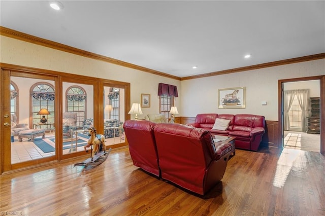 living room with plenty of natural light, crown molding, wood finished floors, and wainscoting