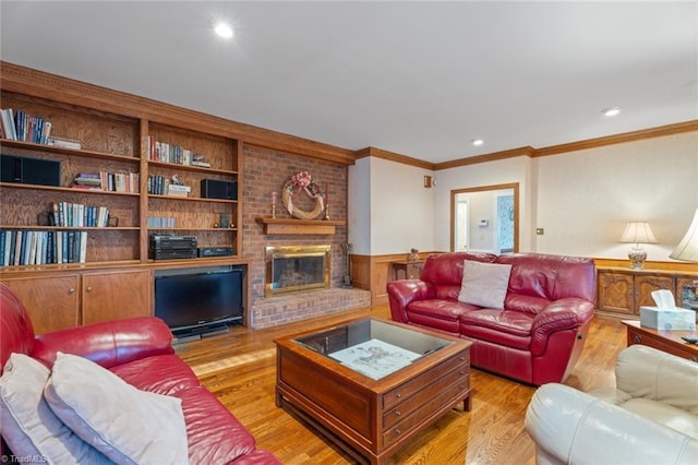 living room featuring built in shelves, a fireplace, wood finished floors, wainscoting, and crown molding