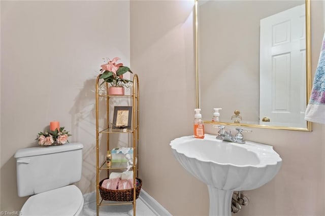 bathroom with toilet, baseboards, and a sink