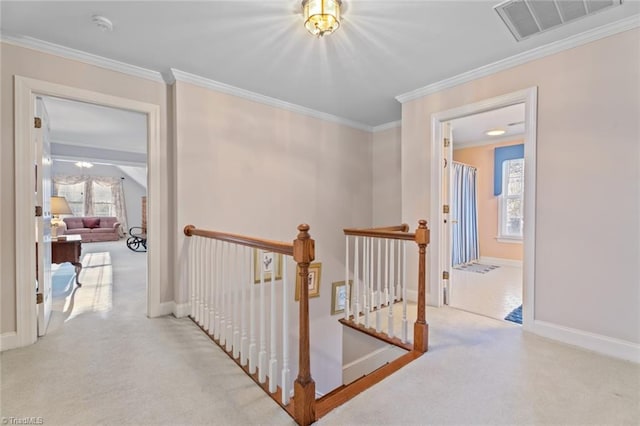 hallway with carpet floors, an upstairs landing, visible vents, baseboards, and ornamental molding