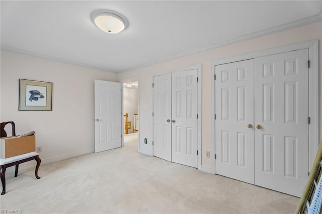 carpeted bedroom featuring baseboards, ornamental molding, and two closets