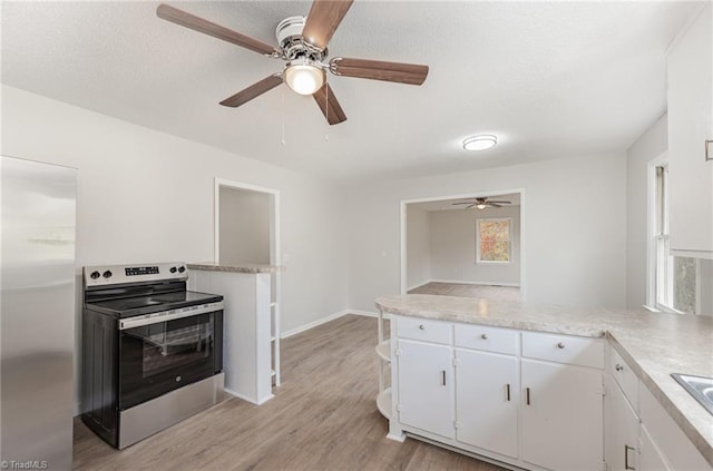 kitchen featuring sink, kitchen peninsula, appliances with stainless steel finishes, white cabinets, and light wood-type flooring