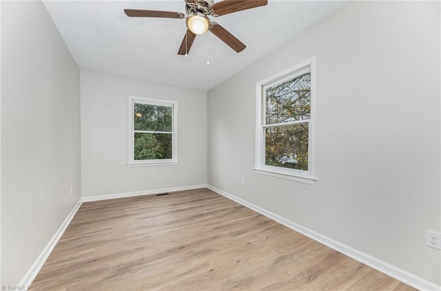 spare room featuring light hardwood / wood-style floors, ceiling fan, and a healthy amount of sunlight