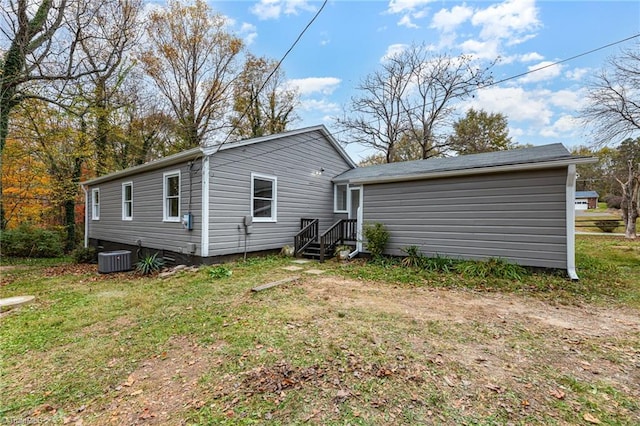 rear view of house with a lawn and central AC