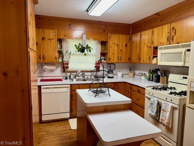 kitchen featuring sink, a kitchen island, white appliances, and light wood-type flooring