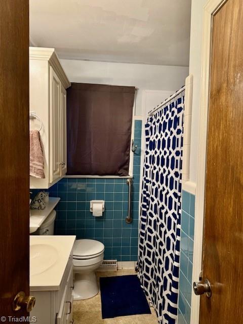 bathroom featuring vanity, tile patterned floors, toilet, tile walls, and walk in shower