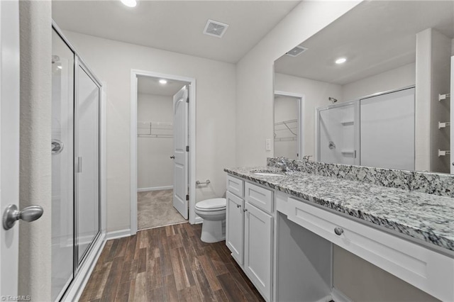 bathroom featuring hardwood / wood-style flooring, vanity, toilet, and walk in shower