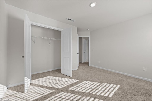 unfurnished bedroom featuring light colored carpet and a closet