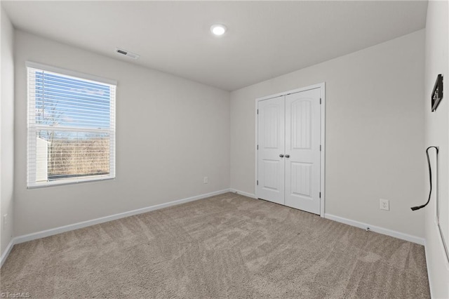 unfurnished bedroom featuring light colored carpet and a closet