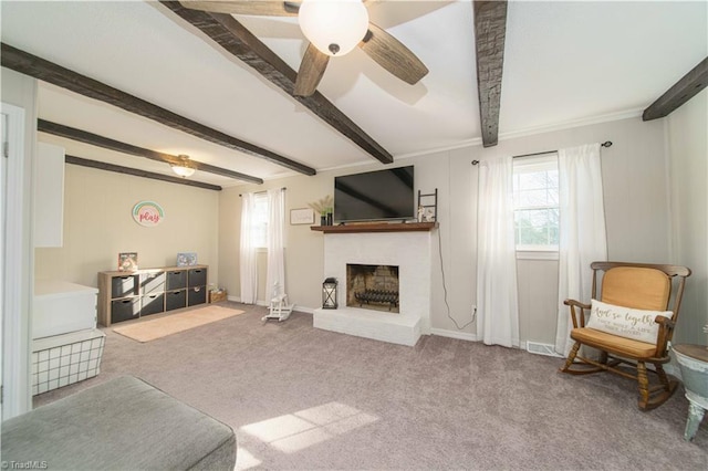 living room featuring beamed ceiling, light carpet, a brick fireplace, and ceiling fan