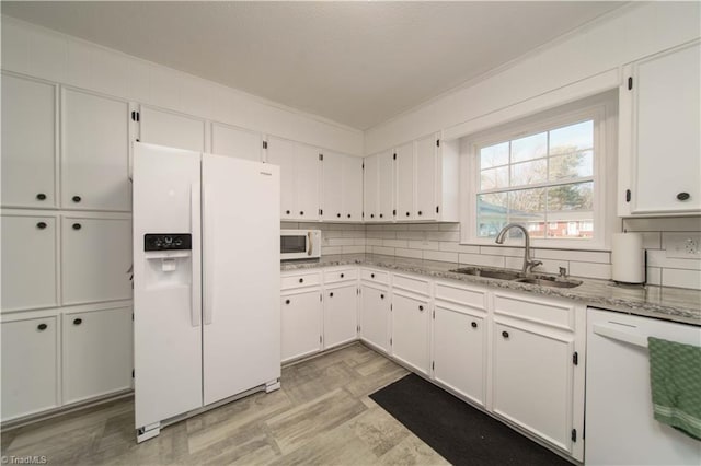 kitchen featuring light stone countertops, decorative backsplash, white appliances, sink, and white cabinetry