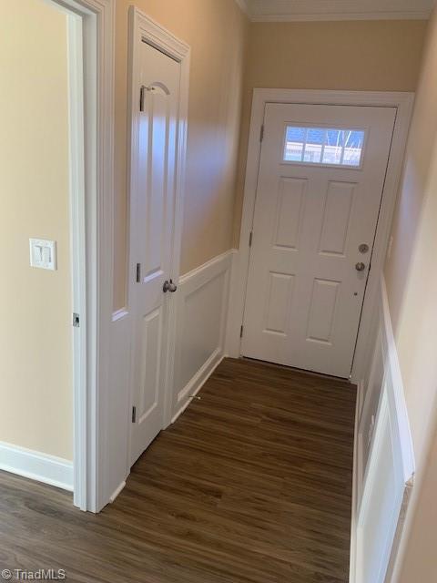 entryway with crown molding and dark wood-type flooring