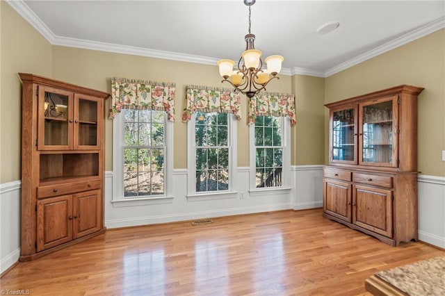 unfurnished dining area featuring light wood-style flooring, visible vents, and ornamental molding