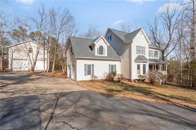 view of front facade with a shingled roof, a porch, a front yard, a garage, and driveway