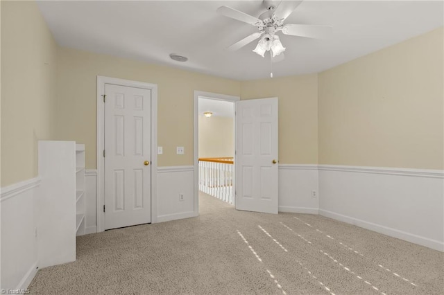 carpeted empty room featuring ceiling fan and baseboards