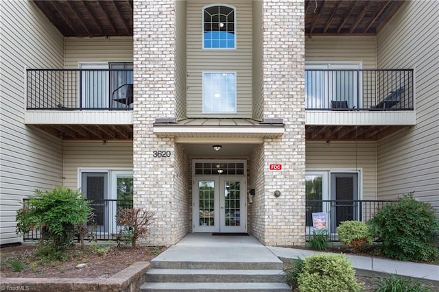 doorway to property with brick siding, french doors, and a balcony