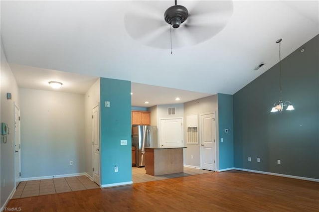 unfurnished living room featuring baseboards, visible vents, ceiling fan with notable chandelier, and light wood-type flooring