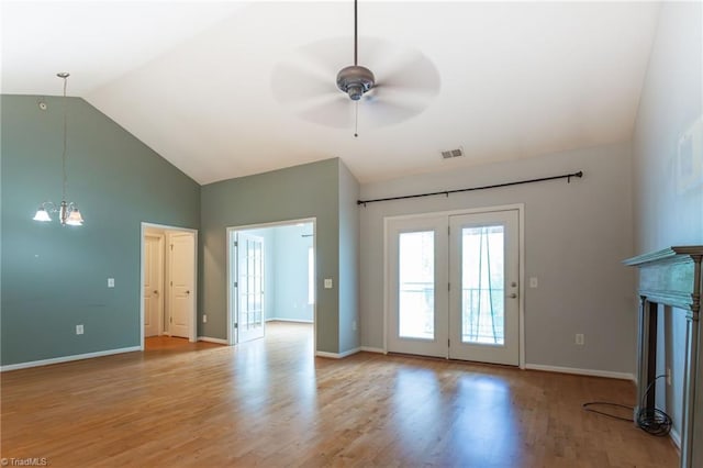 unfurnished living room featuring visible vents, light wood-style floors, baseboards, high vaulted ceiling, and ceiling fan with notable chandelier