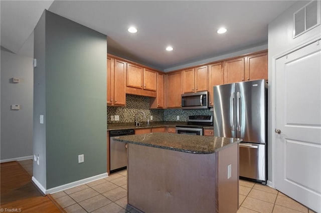 kitchen featuring backsplash, visible vents, appliances with stainless steel finishes, a center island, and light tile patterned floors