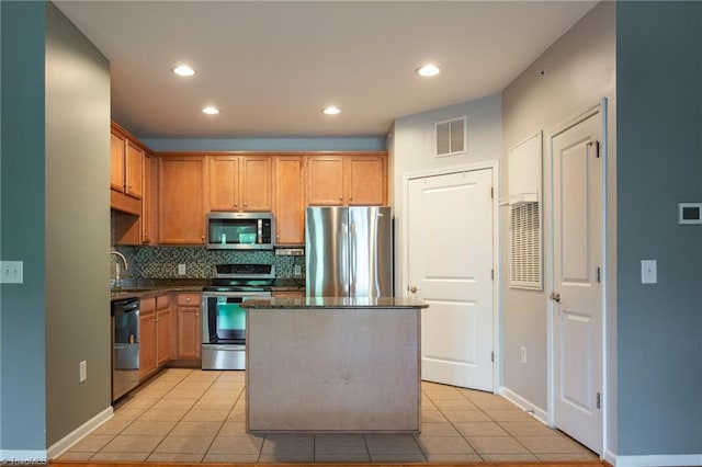 kitchen with appliances with stainless steel finishes, a center island, light tile patterned floors, backsplash, and visible vents