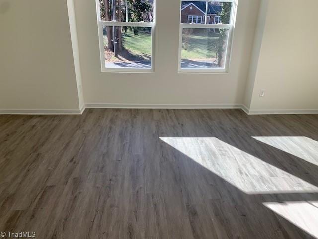 empty room featuring a healthy amount of sunlight and dark hardwood / wood-style flooring