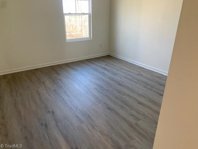 unfurnished room with dark wood-type flooring