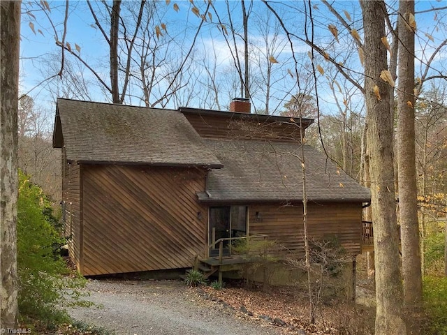 view of side of home with roof with shingles and a chimney