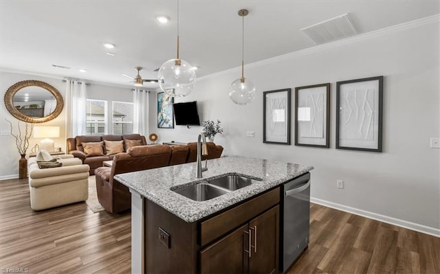 kitchen with dishwasher, an island with sink, light stone countertops, pendant lighting, and sink