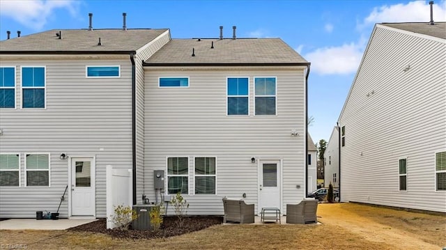 back of house featuring central air condition unit, a patio area, and a lawn