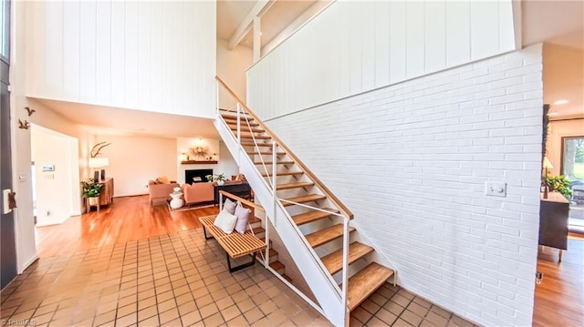 3307 Gaston Rd, Greensboro, NC 27407 - staircase featuring a high ceiling, wood finished floors, brick wall, and a fireplace