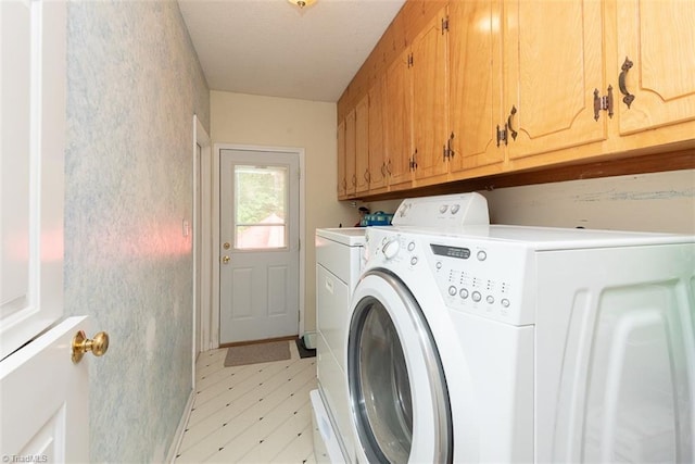 laundry area featuring washing machine and clothes dryer, cabinet space, and light floors