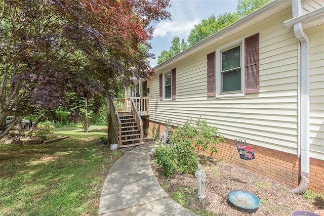 view of side of home with a lawn, a deck, crawl space, and stairs