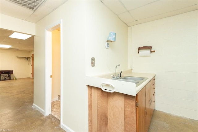 bathroom featuring visible vents, vanity, concrete flooring, a paneled ceiling, and concrete block wall