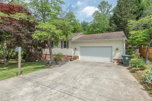 ranch-style home featuring a front yard, a garage, stairway, fence, and concrete driveway