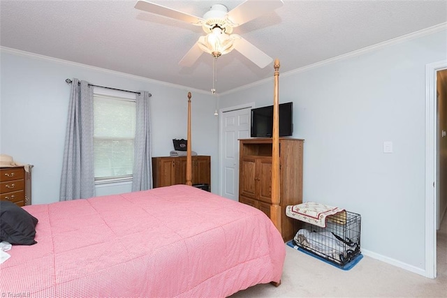 carpeted bedroom with ceiling fan, ornamental molding, baseboards, and a closet