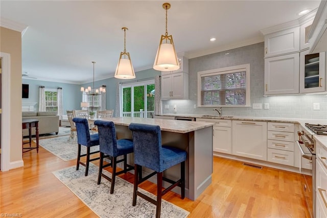 kitchen featuring a sink, a kitchen breakfast bar, high end range, backsplash, and ornamental molding