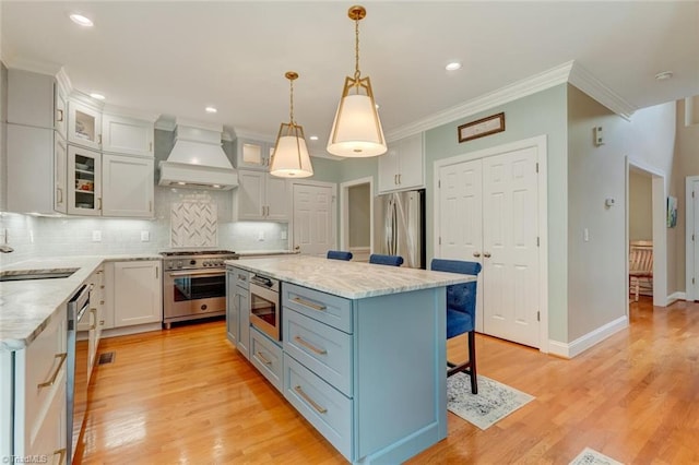 kitchen with crown molding, a breakfast bar area, premium range hood, tasteful backsplash, and appliances with stainless steel finishes