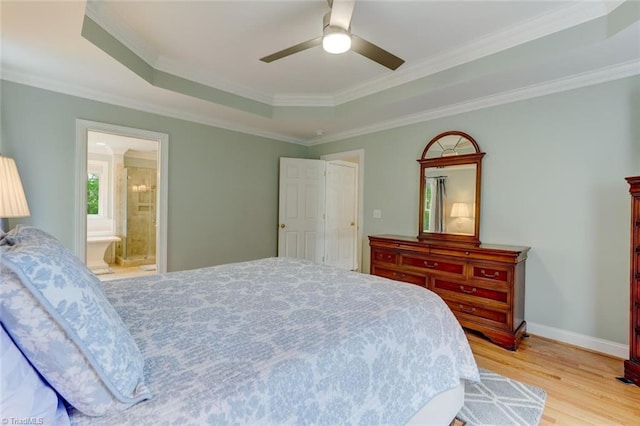 bedroom with baseboards, a tray ceiling, ornamental molding, and light wood-style flooring