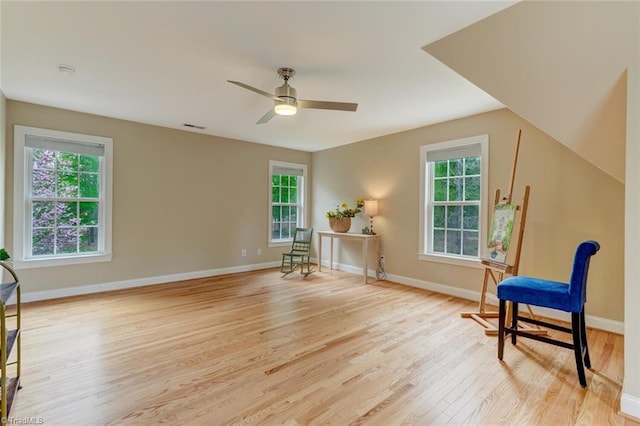 living area featuring plenty of natural light, baseboards, and light wood-type flooring