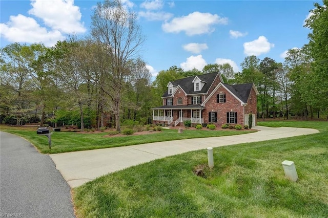 view of front of house featuring brick siding, a garage, a front yard, concrete driveway, and covered porch