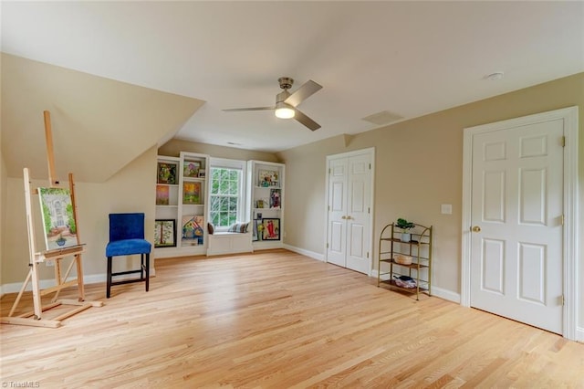 living area with baseboards, ceiling fan, wood finished floors, and vaulted ceiling