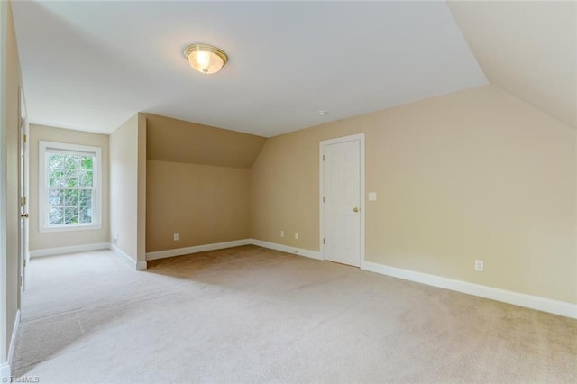 bonus room featuring baseboards, vaulted ceiling, and light colored carpet