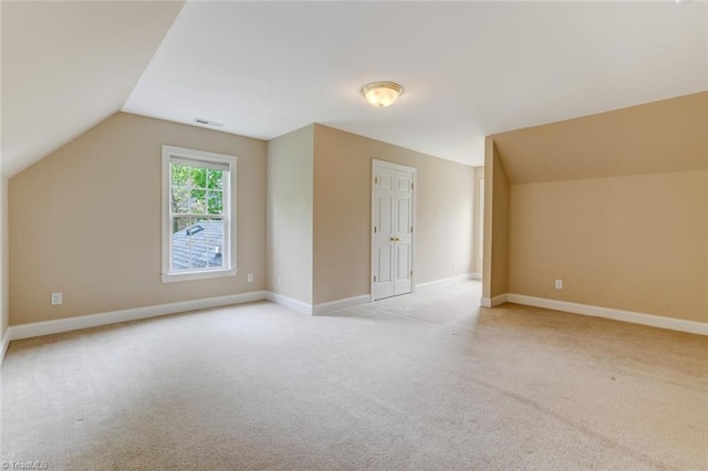additional living space with light colored carpet, vaulted ceiling, and visible vents