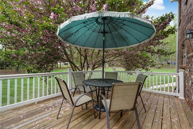 wooden deck with a lawn and outdoor dining area