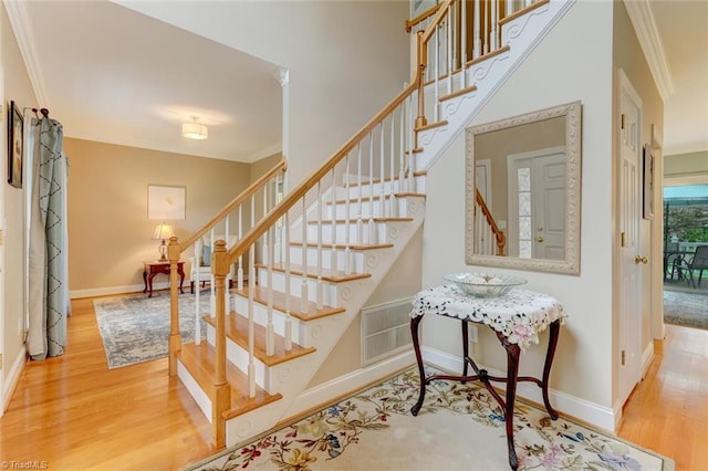 stairs with baseboards, visible vents, ornamental molding, and wood finished floors