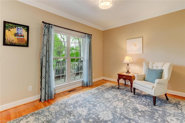 living area featuring baseboards, ornamental molding, wood finished floors, and visible vents
