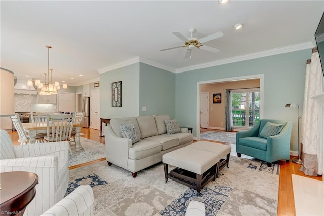 living room featuring crown molding, baseboards, recessed lighting, light wood-type flooring, and ceiling fan with notable chandelier