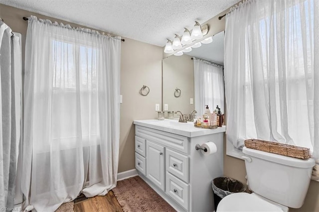 bathroom featuring toilet, wood-type flooring, a textured ceiling, and a wealth of natural light