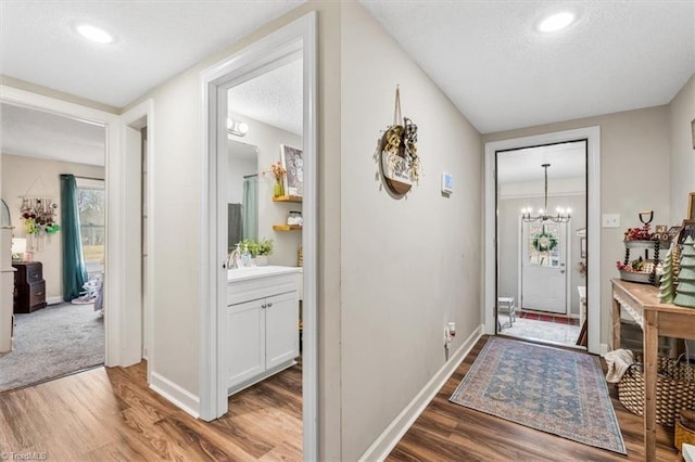 foyer entrance with sink, wood-type flooring, a textured ceiling, and an inviting chandelier